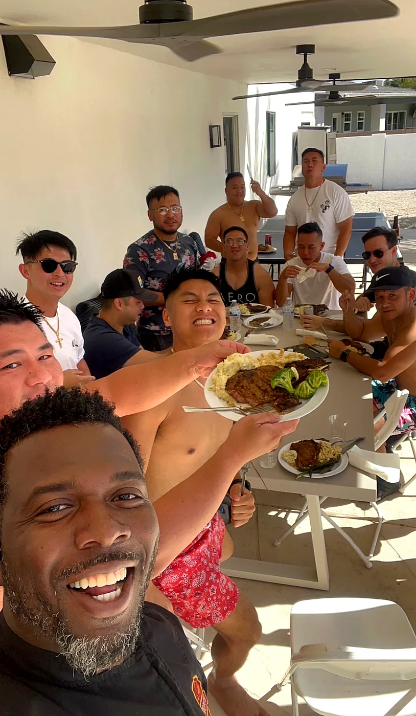 Chef Terry taking a selfie with a cheering group of friends around a patio table at a backyard pool party