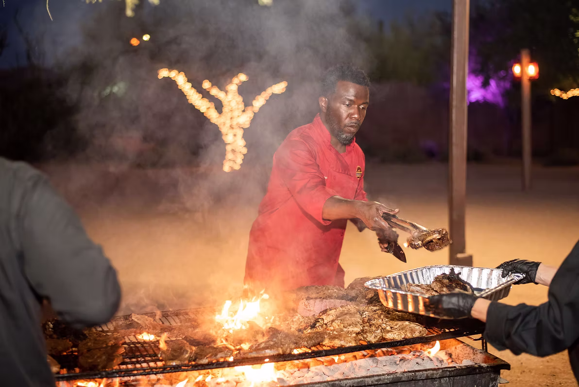 Pitmaster's view from the live-fire grill — wood-fired steaks and chicken catered on-site by Qfire Catering