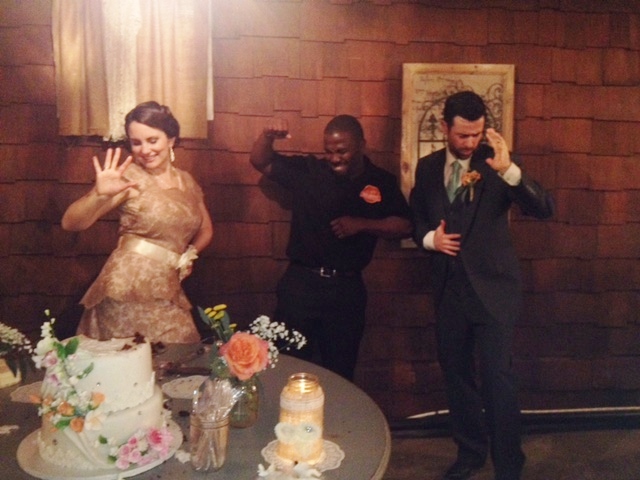 The BBQ Daddy cutting the wedding cake with the couple