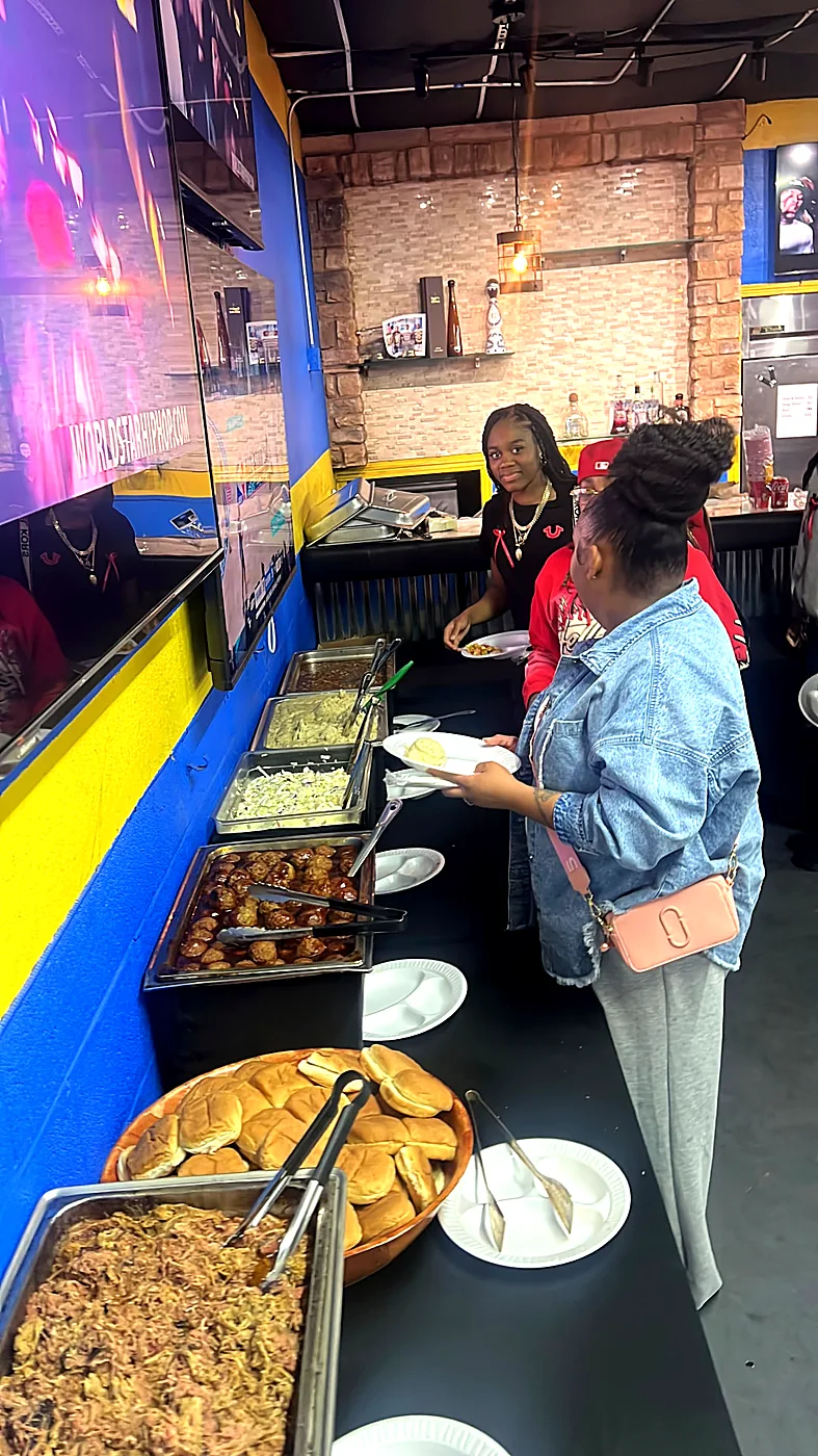 Guests serving themselves from a hot buffet line with rice, meats and rolls at a private venue party