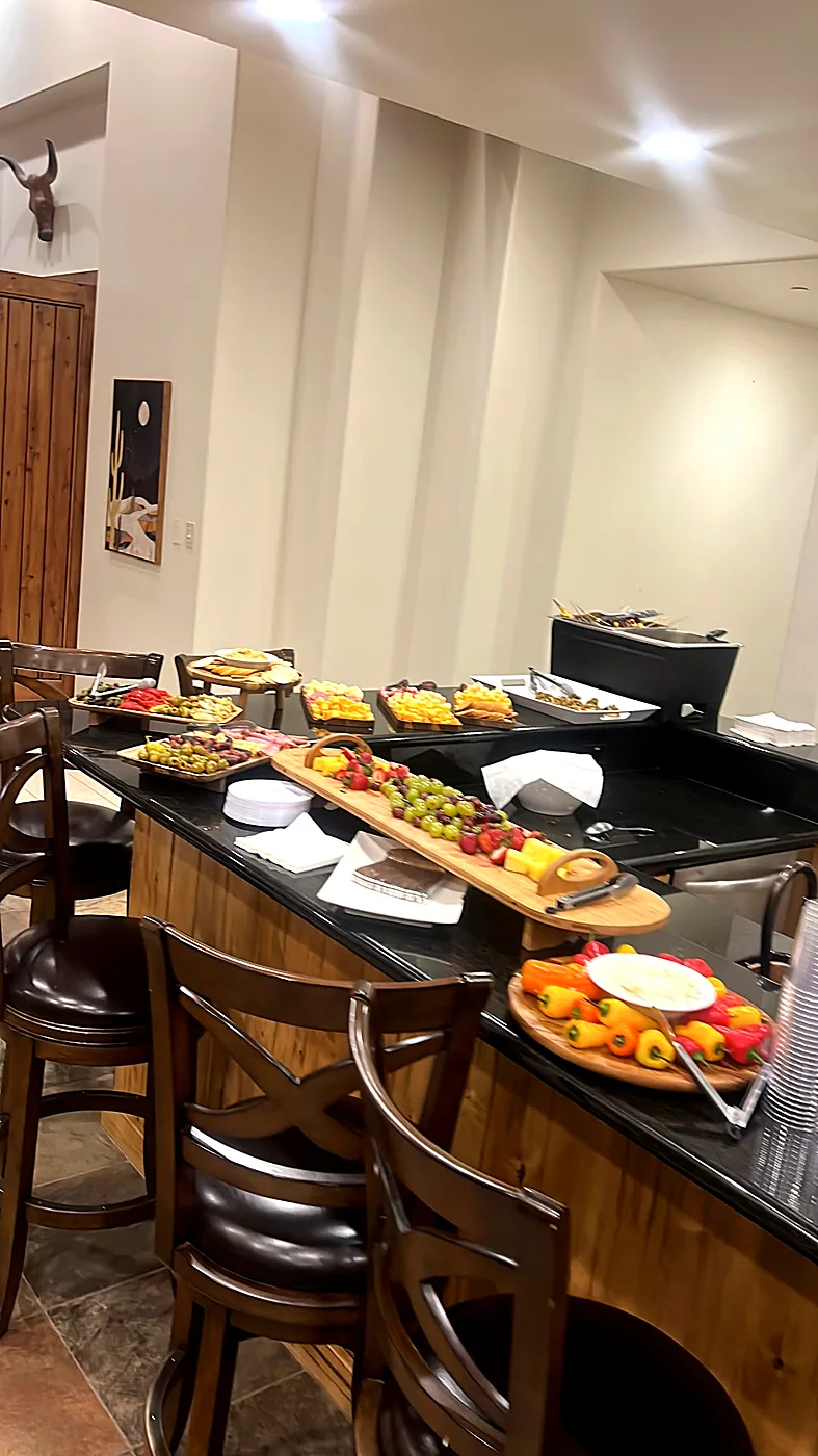 A catered buffet with skewers, platters and chafing dishes set along a kitchen island in a private home