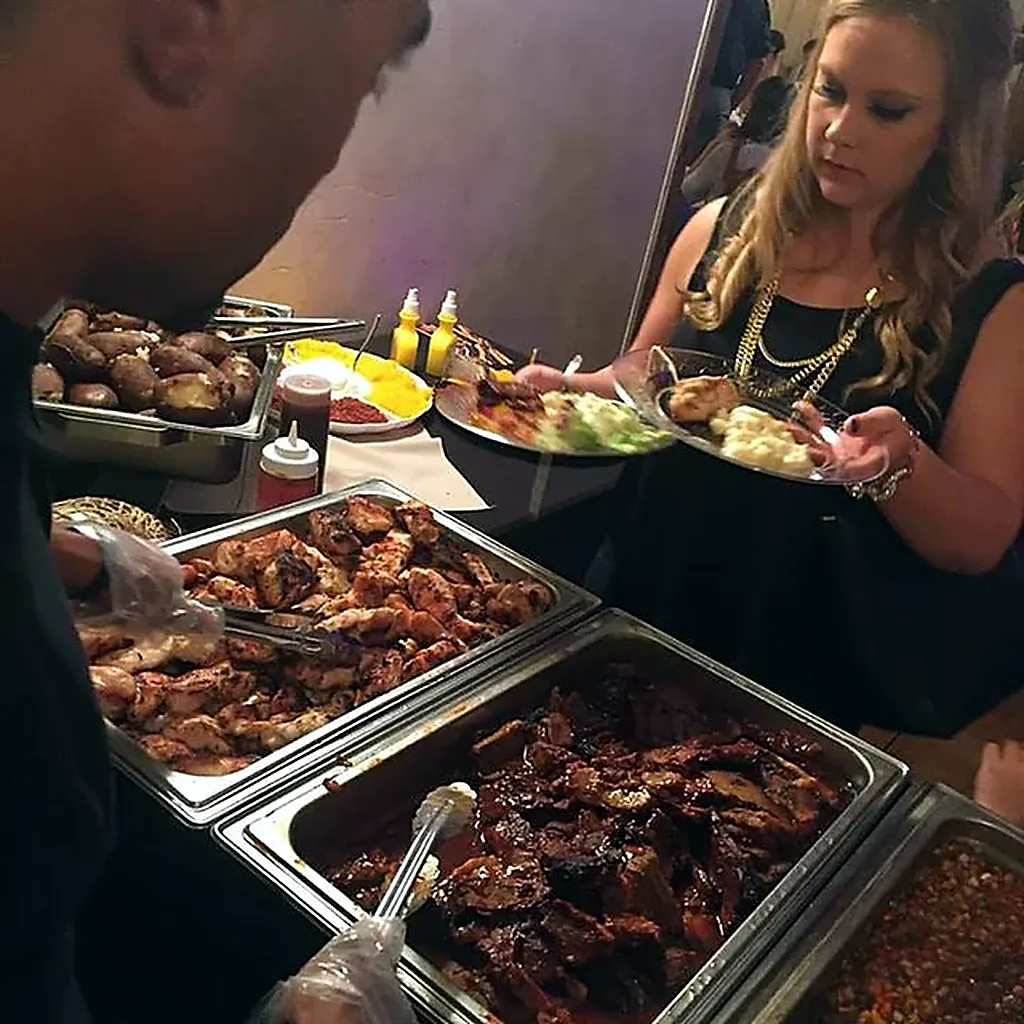 Grilled chicken, glazed BBQ and baked potatoes served from chafing dishes as a guest fills her plate