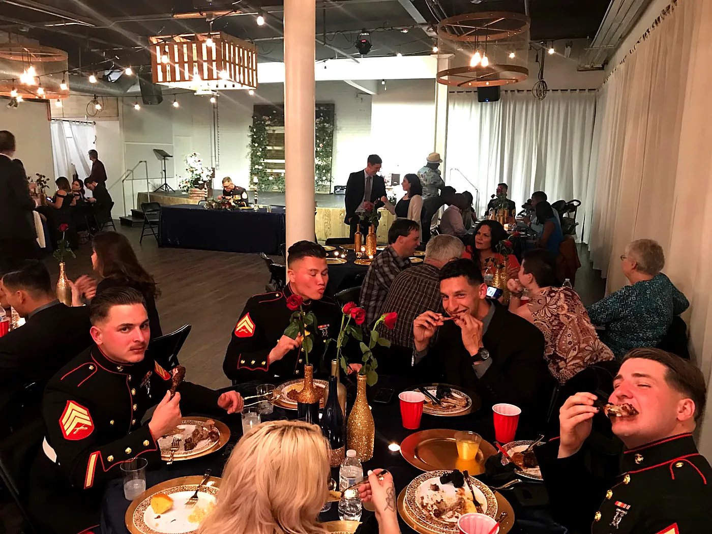 Marines in dress blues and their guests enjoying a catered dinner at a private banquet