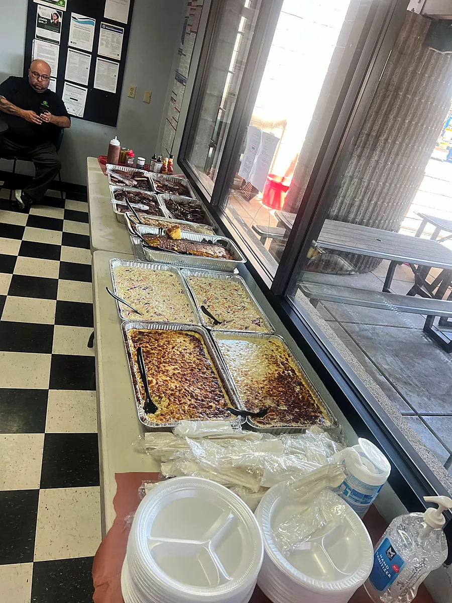 Trays of smoked meats, cornbread, coleslaw and mac and cheese set up in a company breakroom