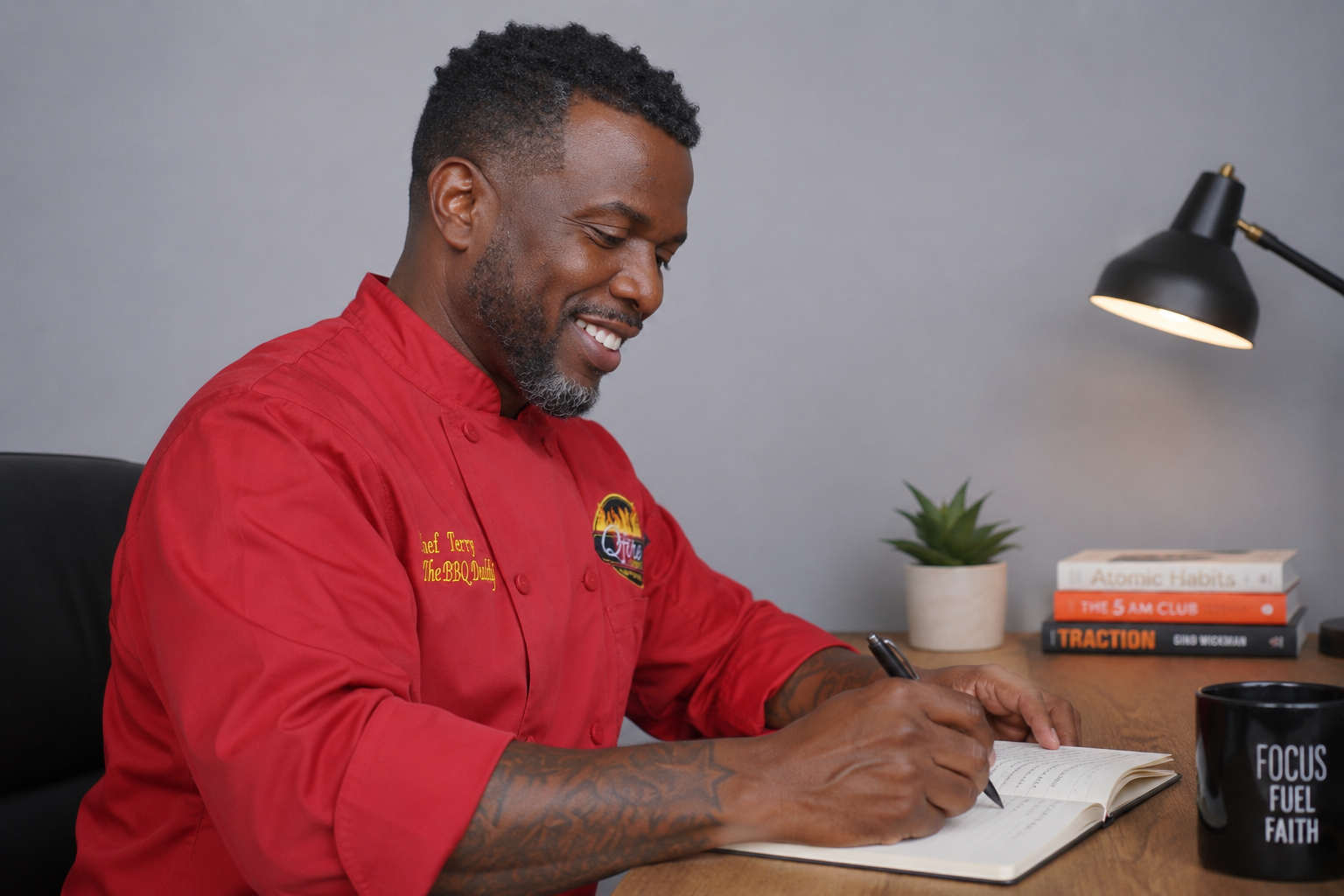 Chef Terry Matthews, The BBQ Daddy, writing catering notes at his desk