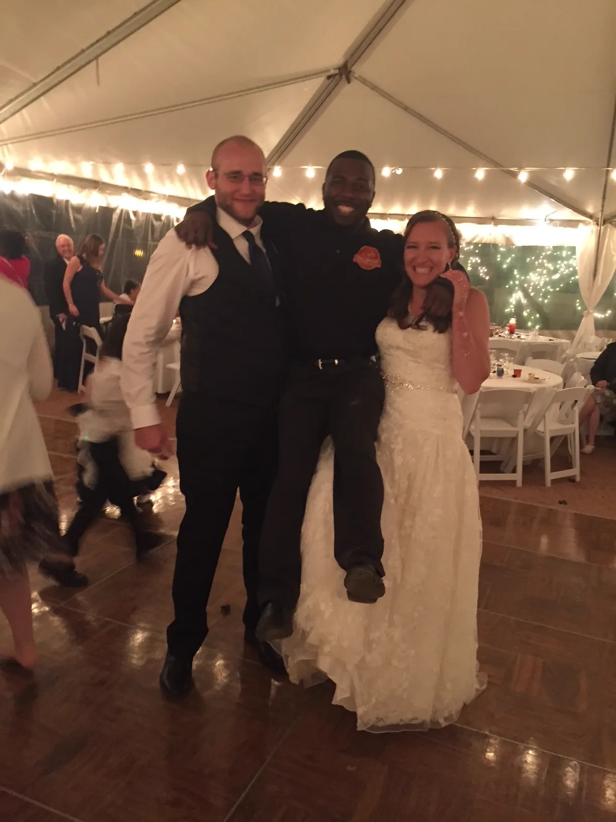 The BBQ Daddy dancing with bride and groom under tent string lights at a Phoenix Metro wedding